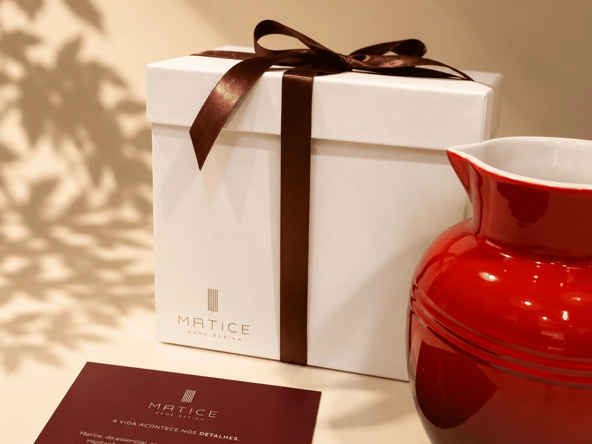 Presente Matice com embalagem branca, laço marrom e peça vermelha.